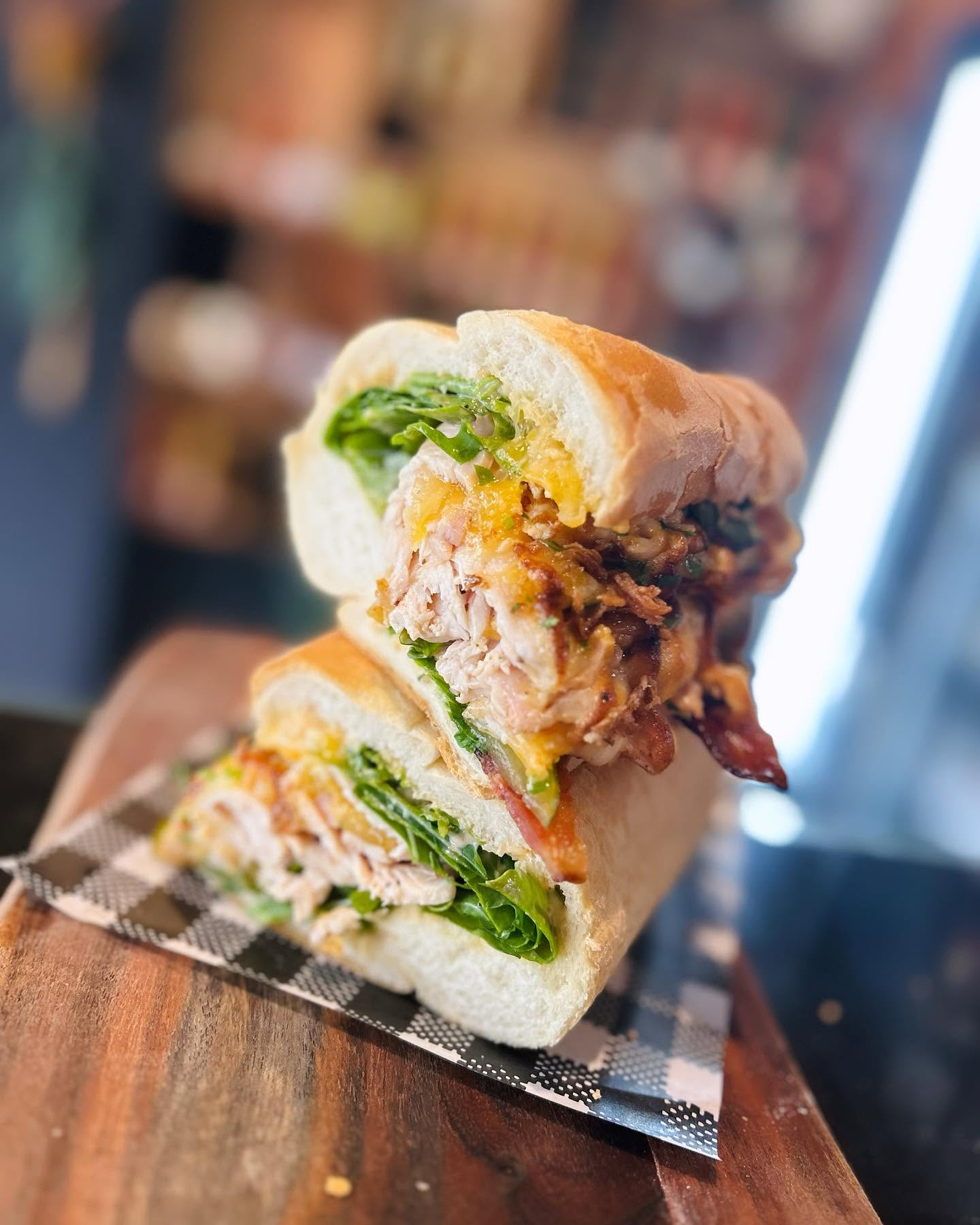Fresh gourmet sandwich with turkey, cheese, lettuce, and tomato on a wooden board